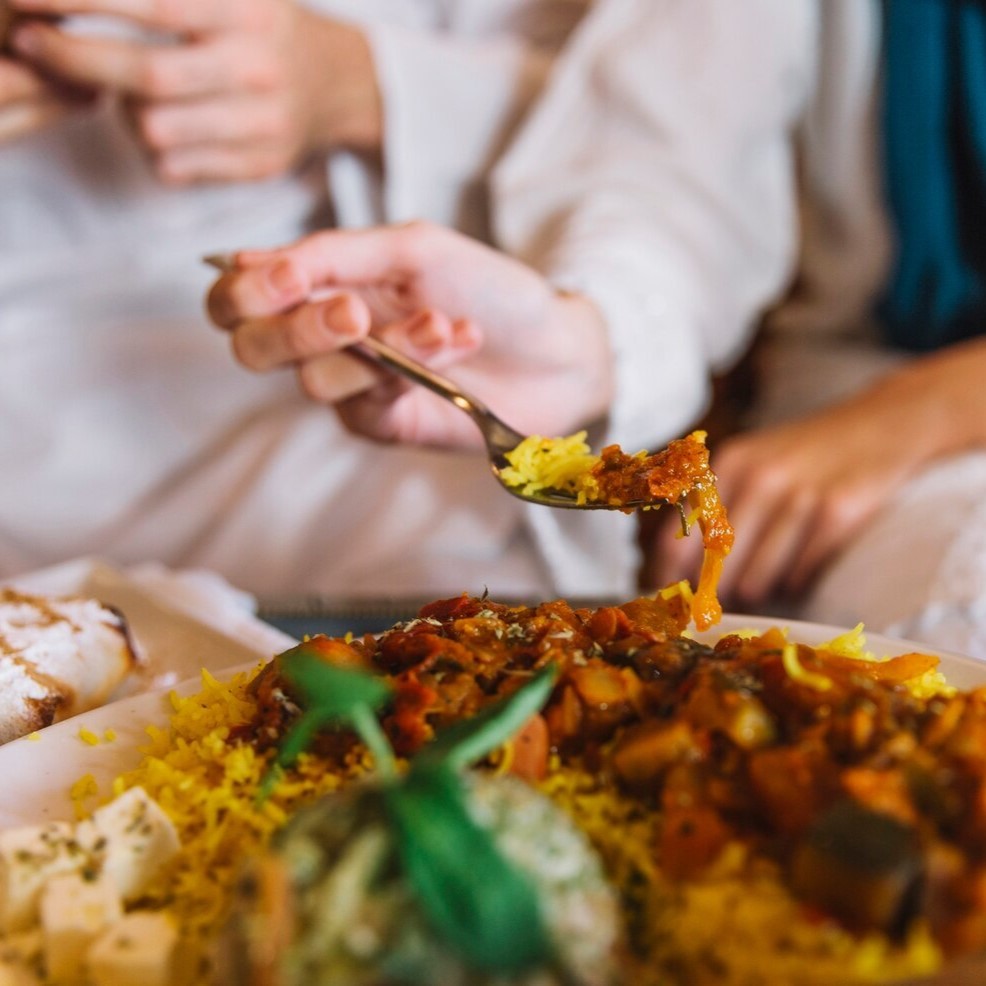 Close-up of a person enjoying a traditional Arabic or fusion meal, emphasizing hospitality and culinary tourism.