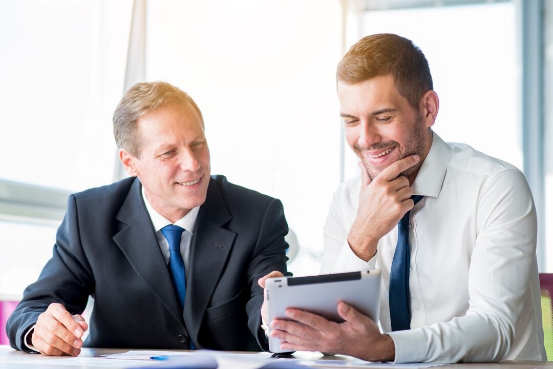 Brokerage advisors discussing investment opportunities using a digital tablet.