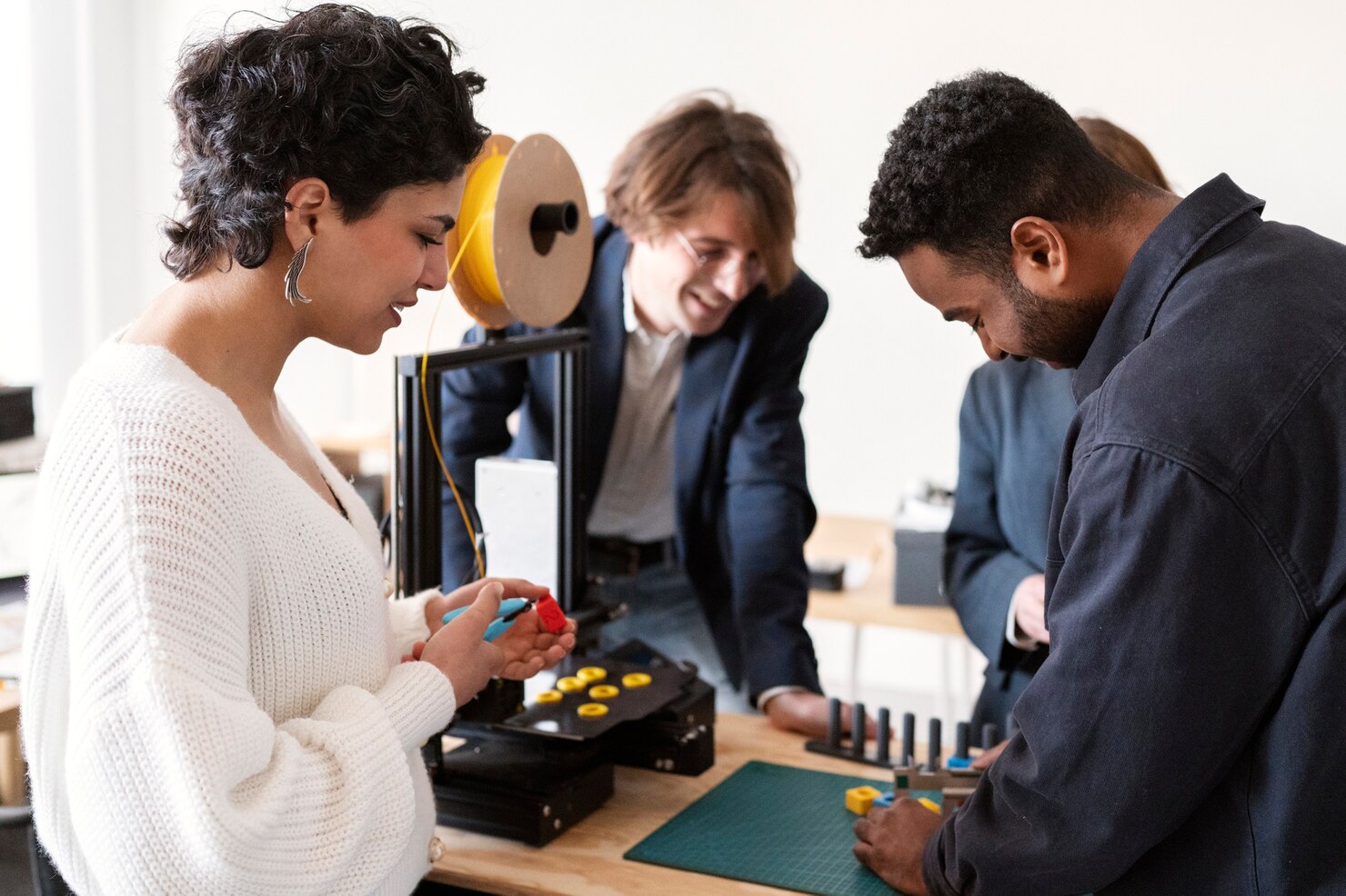 Incubation team collaborating on product design and innovation using a 3D printer.