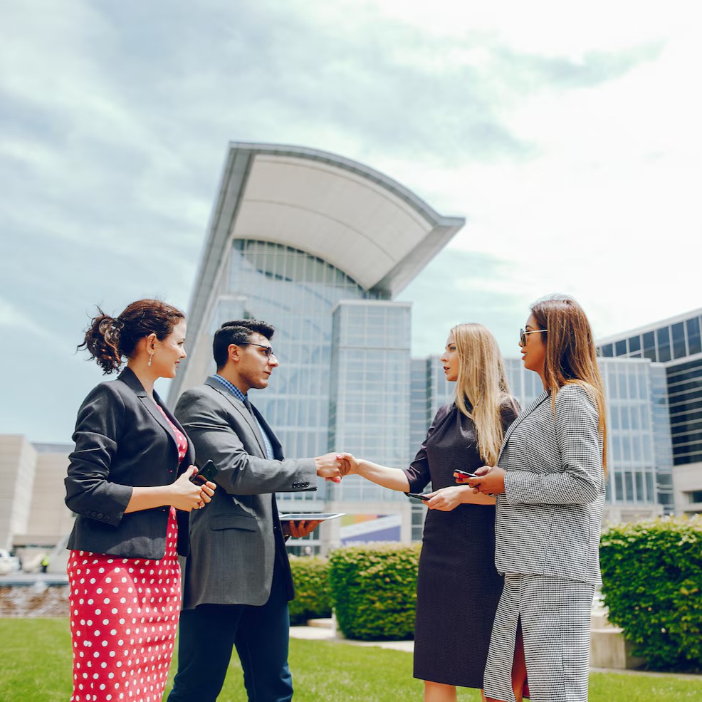 Business partners shaking hands outside a modern convention center, symbolizing Tourism and Hospitality investment and collaboration.