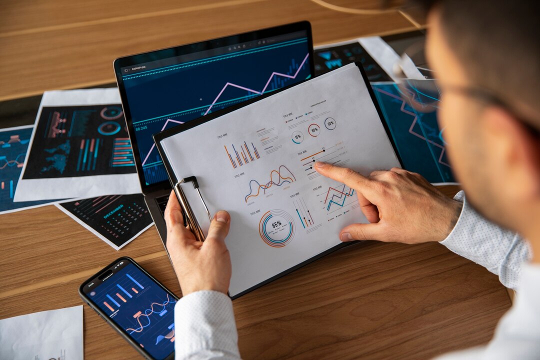 Brokerage analyst reviewing digital financial reports and performance charts on multiple devices.