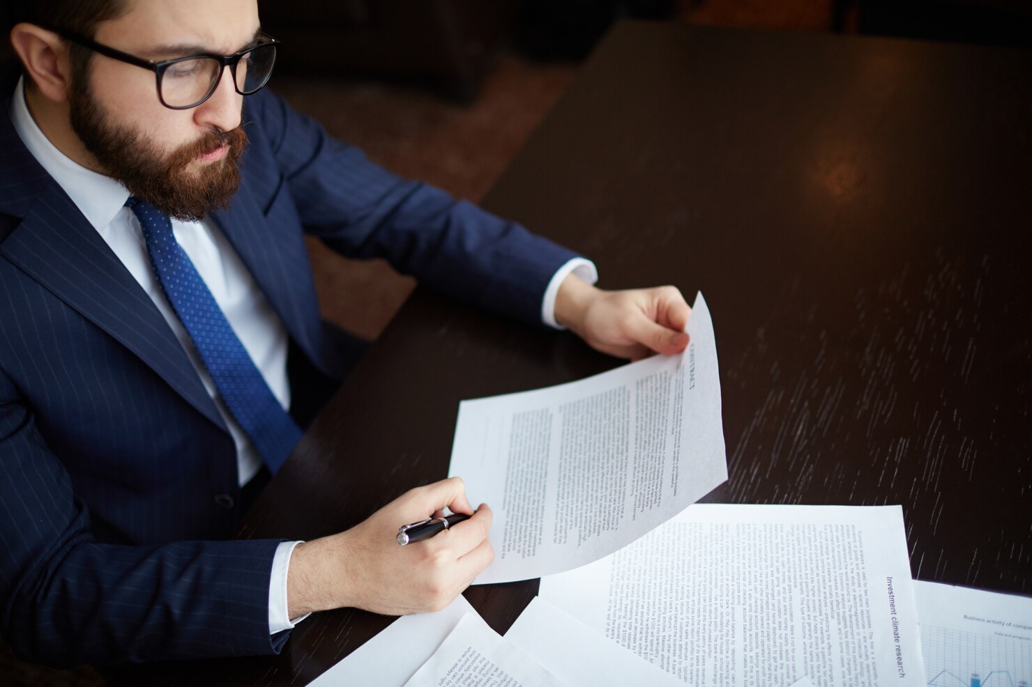 Commercial professional reviewing legal and business documents at office desk.